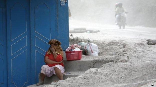 A woman covers her nose and mouth from volcanic ash from the eruption of Mount Sinabung in Sibintun, North Sumatra, Indonesia, Sunday, Jan. 19