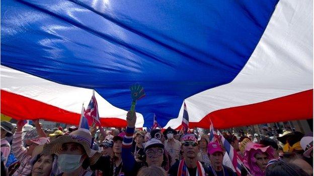 Thai anti-government protesters carry a large national flag as they parade during a rally in Bangkok on January 25