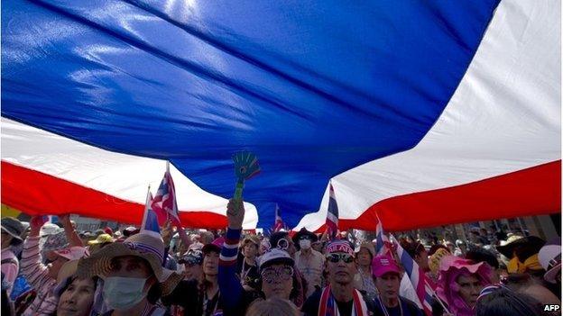 Thai anti-government protesters carry a large national flag as they parade during a rally in Bangkok on January 25