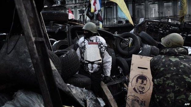 Anti-government protesters stand guard at a road bloc barricade in Kiev