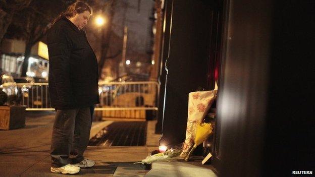 A man mourns in front of flowers placed in memory of actor Philip Seymour Hoffman