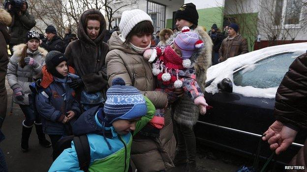 Women and children walk outside the school where the shooting incident happened