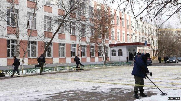 A security service member uses a mine and metal detector as he works near the building of a high school, where a shooting incident has occurred, on the outskirts of Moscow