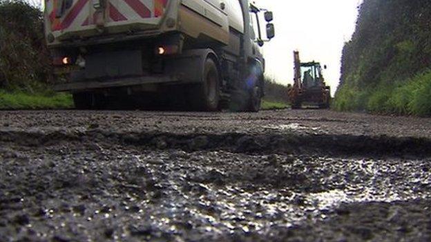 Roadworks truck approaches large pothole