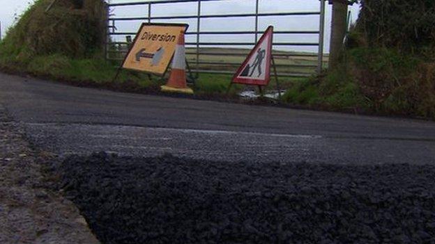 Roadworks signs next to repaired pothole