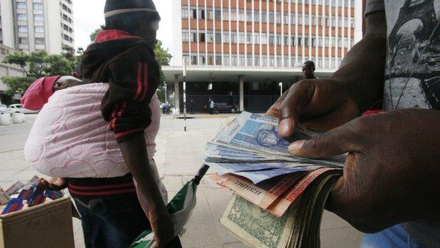 Someone holding South African rand and US dollars in Zimbabwe's capital, Harare