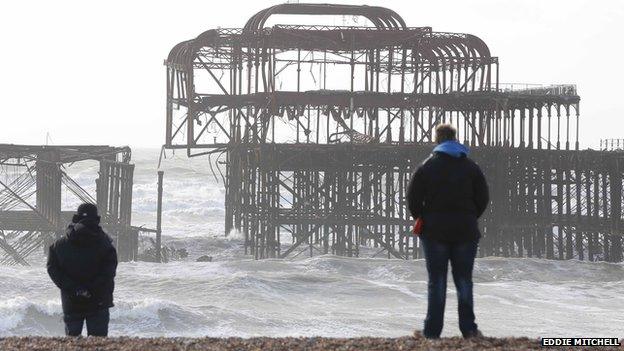 People looking at the new damage to the pier