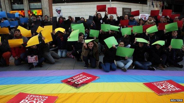 Demonstrators pose with the pieces of paper in the colours of the Olympic rings during a protest in Madrid against Russia's anti-gay laws ahead of the Sochi 2014 Olympic Games on 5 February 2014.