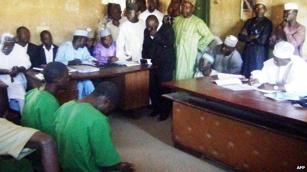 A picture taken on 22 January 2014 shows two suspected homosexuals in green prison uniforms (L) sitting before a judge in Bauchi, Nigeria