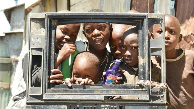 Children peeking through a broken TV set