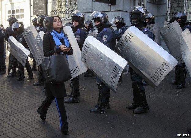 A woman passes riot police in Kiev, 6 February