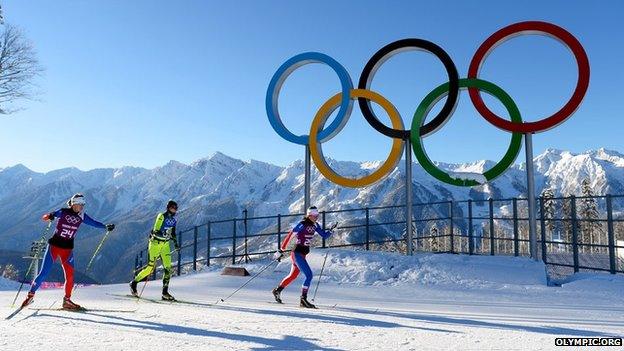 Cross country skiers in front of Olympic rings