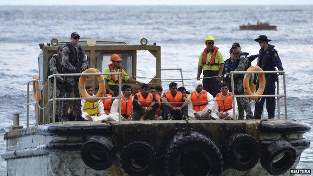 File photo: Australian customs officials and navy personnel escort asylum-seekers onto Christmas Island after they were rescued from a crowded boat that had foundered at sea, 21 August 2013