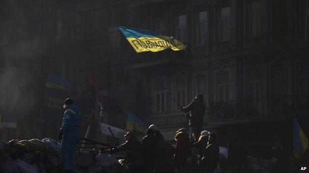 An opposition supporter waves an Ukrainian flag on top of a barricade in a street heading to Kiev's Independence Square, the epicentre of the country's current unrest, Ukraine, Thursday, Feb. 6, 2014.