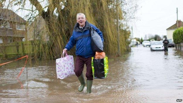 A man walks through flooded streets in the village of Moorland in Somerset