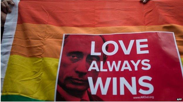 An activist holds a flag displaying a placard with a slogan over the face of Russian President Vladimir Putin during a demonstration against Russia's anti-gay legislation, in Hong Kong on 7 February