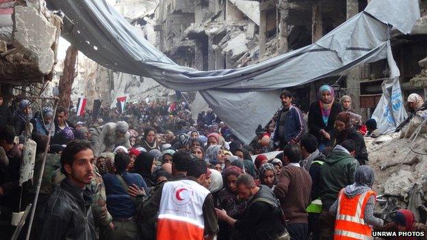 Crowds of Yarmouk camp residents wait to be allowed to join the queue for aid distribution