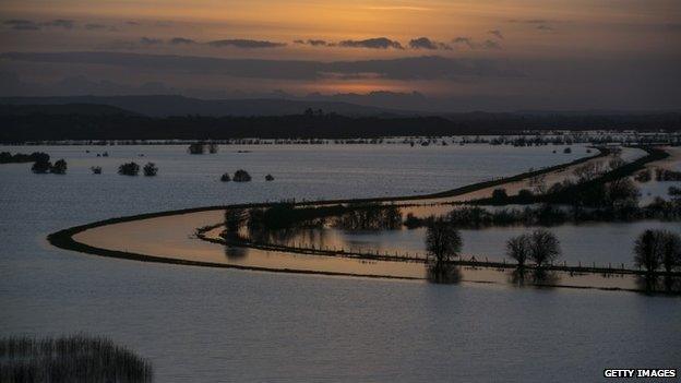 The sun sets over flooded fields surrounding the River Tone on the Somerset Levels.