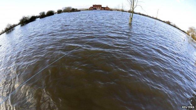 A property is seen completely surrounded by flood water in the village of Moorland in south west