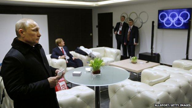 Russian President Vladimir Putin waits in the presidential lounge to be introduced at the opening ceremony of the Sochi 2014 Winter Olympics as a television screen displays five Olympic rings (7 February 2014)