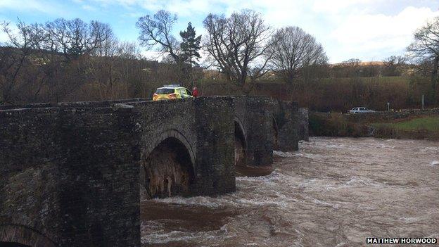 Police car on closed bridge over swollen river