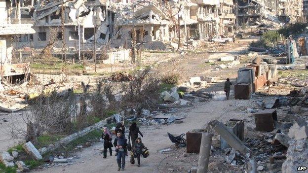 Civilians leave the the besieged district of the central Syrian city of Homs ahead of being evacuated by United Nations staff on 9 February 2014