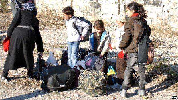 Civilians wait to be evacuated by United Nations staff from the besieged district of the central Syrian city of Homs 9 February 2014