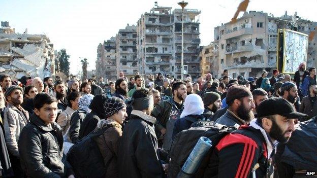 Civilians wait to be evacuated by United Nations staff from the besieged district of the central Syrian city of Homs on 9 February 2014