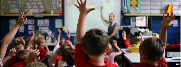 Children put up their hands in a school classroom