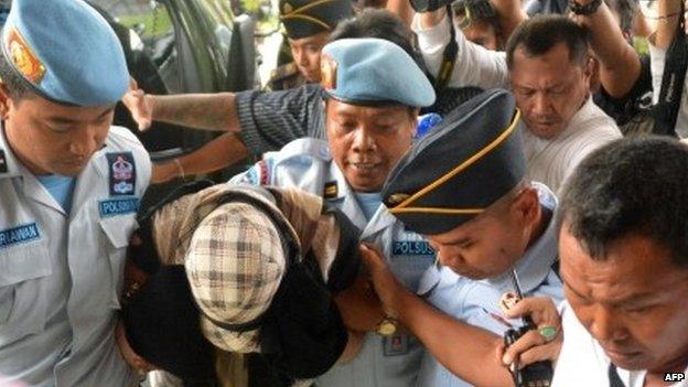 Australian drug trafficker Schapelle Corby (centre) is escorted by police and prison officials at the prosecutor's office on 10 February 2014