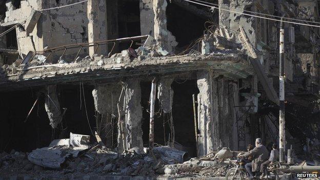 Residents ride a motorcycle along a damaged street in Deir al-Zor, eastern Syria