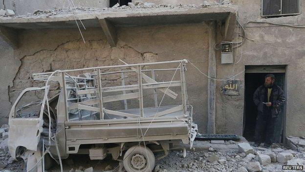 A man inspects damage after what activists said were explosive barrels thrown by forces loyal to Syria"s President Bashar al-Assad in the Al-Shaar neighbourhood of Aleppo