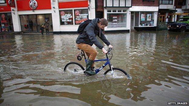 A cyclist rides through floodwater in Datchet