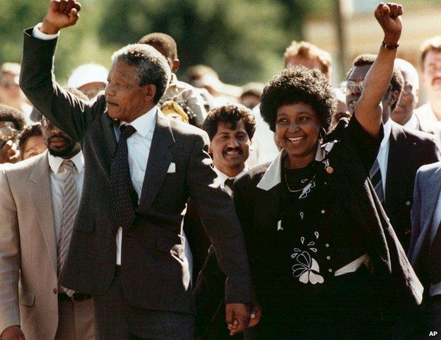 Nelson Mandela and his wife, Winnie, raise clenched fists as they walk hand-in-hand upon his release from prison