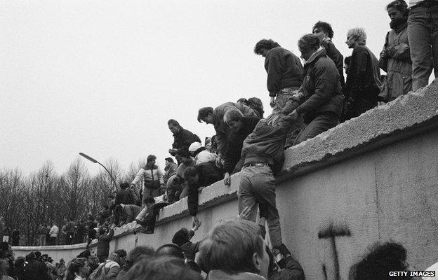 East Berliners climb onto the Berlin Wall to celebrate the effective end of the city's partition