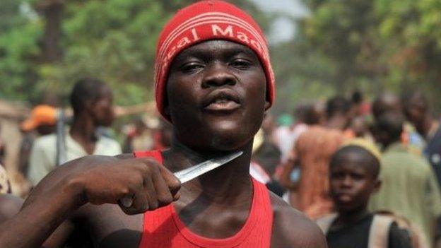 A man holds a knife to his throat claiming that he is looking for Muslims to cut off their heads in the 5th district of Bangui on February 9, 2014.