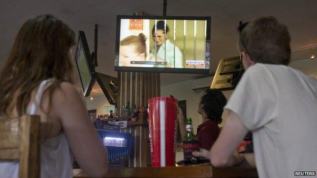 Australian tourists watch a television news report on convicted Australian drug trafficker Schapelle Corby at a bar in Seminyak, Bali on 9 February 2014