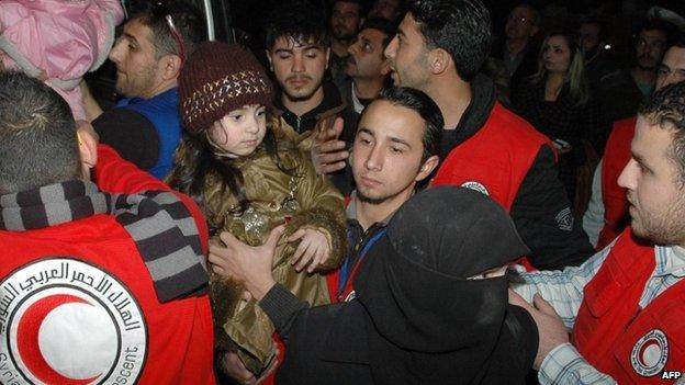 Syrian Red Crescent staff help civilians exit a bus after they were evacuated from rebel-controlled, army-besieged districts of Homs, on 10 February 2014