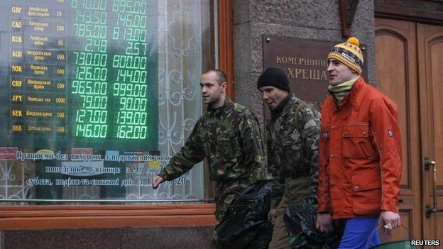 Anti-government demonstrators walk past a currency exchange office in Kiev February 7, 2014.