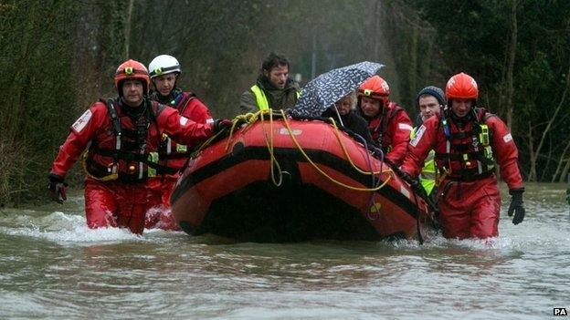 Firefighters rescue a woman from her house in Wraysbury, Berkshire