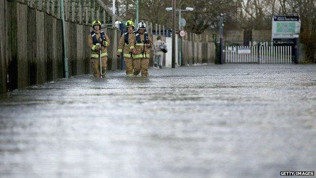 Firefighters walking down flooded street in Chertsey