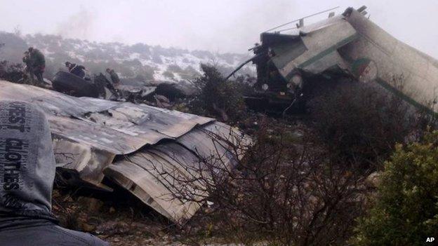 A man watches rescue workers working at the wreckage of Algerian military transport aircraft after it slammed into a mountain in the country's rugged eastern region