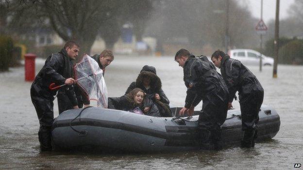 Soldiers from the Royal Engineers help residents through a flooded road in Egham