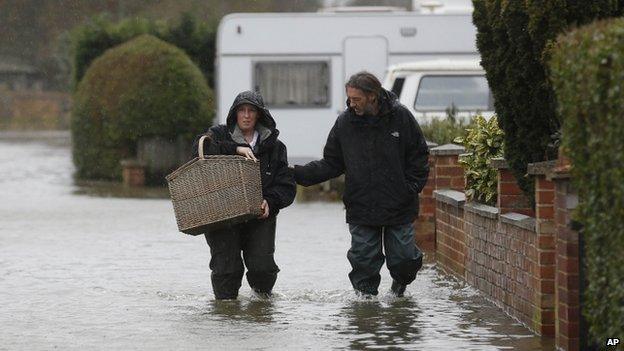 Residents in Egham make their way through a flooded street