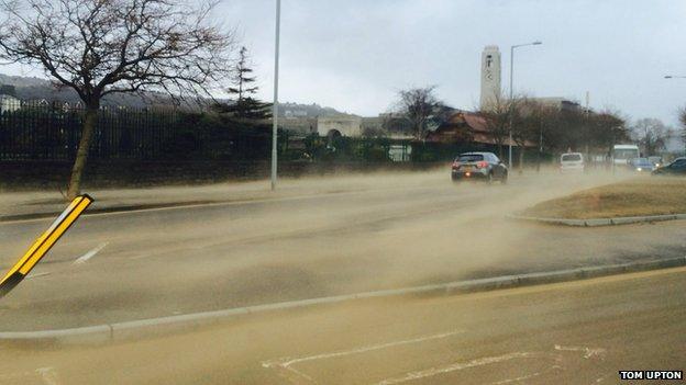 Sand is blown across Mumbles Road and beyond during strong winds in Swansea