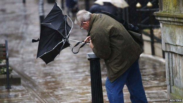 A man struggles to control his umbrella in Windsor, Berkshire