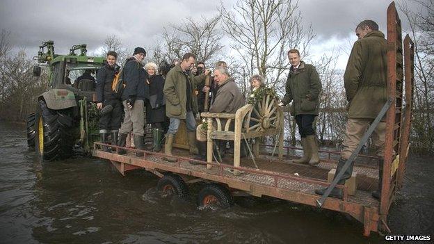 Prince Charles sits on a tractor trailer as he visits the flood hit village of Muchelney