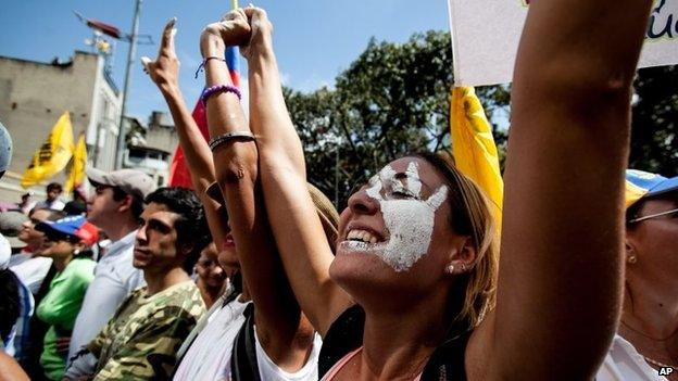 A woman with the symbol of the student protests, a white hand, painted on her face marches with fellow demonstrators to the General Prosecutors building in Caracas, Venezuela, on Wednesday 12 February, 2014