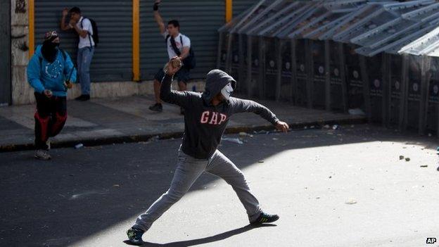 Demonstrators throw rocks at riot police during clashes between opposition protesters with security forces and pro-government supporters during a protest against the government in Caracas on 12 February, 2014