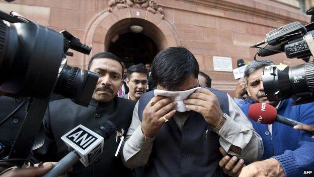 An unidentified member of India"s Parliament, holding a handkerchief to his face after being affected by pepper spray, leaves Parliament after protests inside the building in New Delhi on February 13, 2014